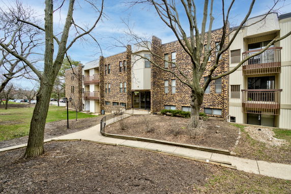 Front view of a multi-story brick apartment building with balconies.