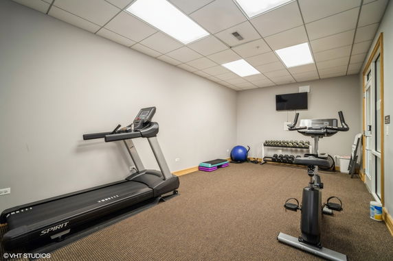 Indoor gym area with treadmill, exercise bike, and weights.