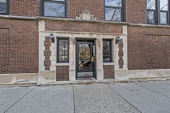 Front view of a brick building entrance with decorative stonework around the door.