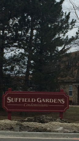 Front view of a condominium building with a sign reading 'Suffield Gardens Condominiums.'