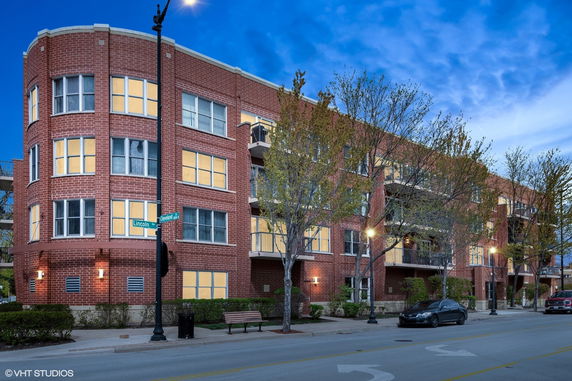 Front view of a red brick multi-story residential building with balconies.