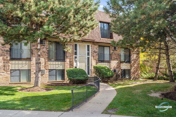 Front view of a multi-story brick apartment building with balconies.