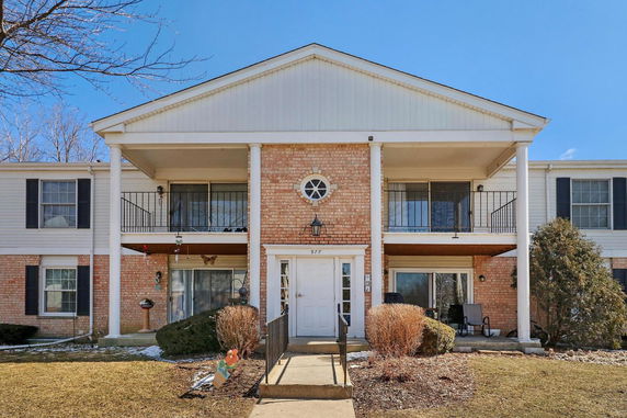 Front view of a two-story apartment building with a central entrance and balconies.