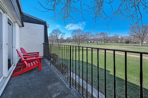 View from a balcony overlooking a grassy field and trees.