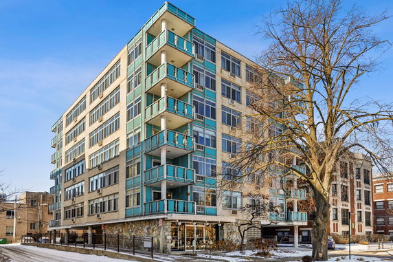 Front view of a multi-story residential building with balconies and large windows.