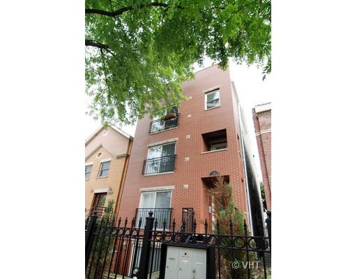 Front view of a multi-story brick building with balconies and a metal fence.
