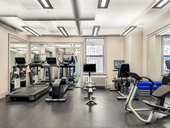 Fitness room with exercise equipment including treadmills and stationary bikes.