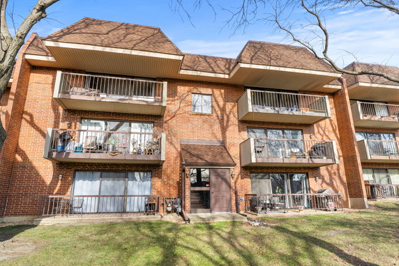 Front view of a three-story brick apartment building with multiple balconies.
