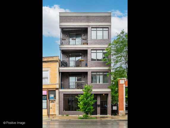 Front view of a multi-story brick building with balconies.