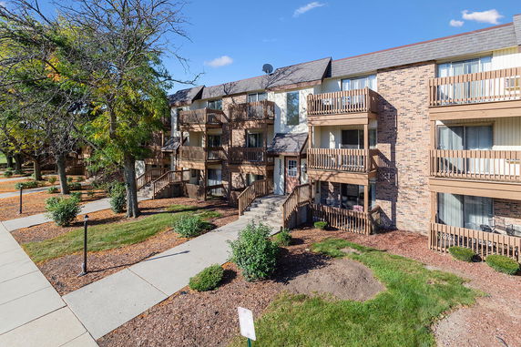 Front view of a three-story apartment building with balconies and brick exterior.