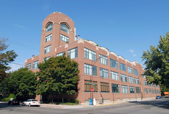 Front view of a multi-story brick building with large windows.