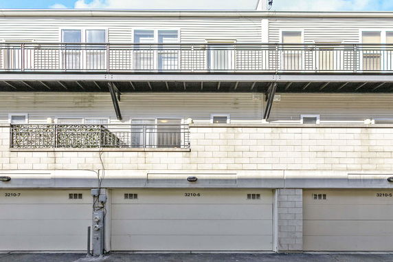 Front view of a multi-story building with garages on the ground floor.