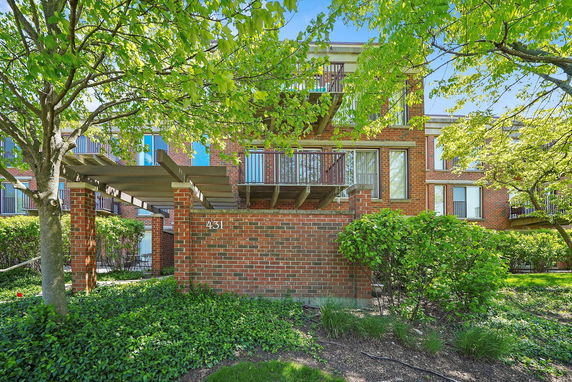 Front view of a brick residential building with multiple balconies and a pergola entrance.