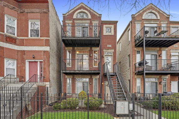 Front view of a multi-story brick building with balconies and external staircase.