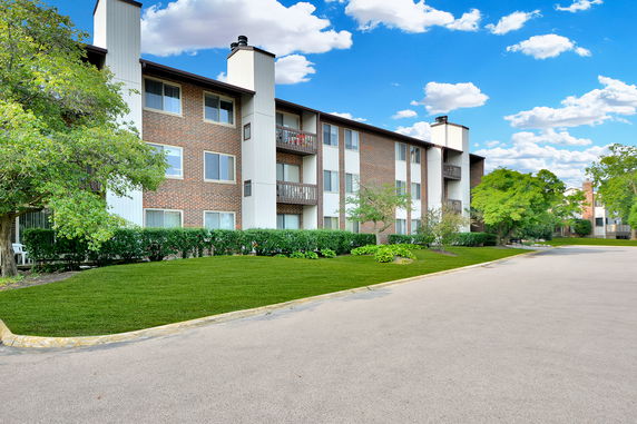 Front view of a multi-story apartment building with balconies and brick facade.