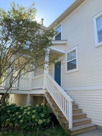 Front view of a two-story house with a staircase leading to the entrance.