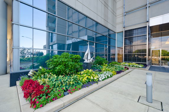 Front view of a building with large glass windows and a landscaped garden area.