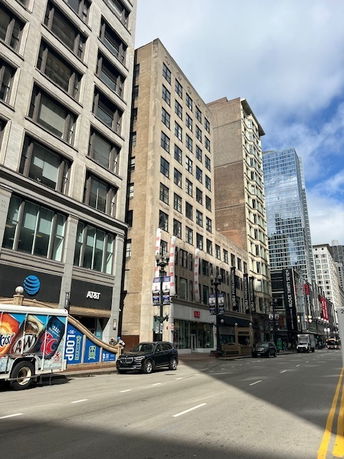 Street view of tall commercial buildings with retail stores at ground level.