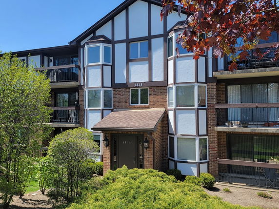 Front view of a multi-story residential building with balconies and a brick façade.