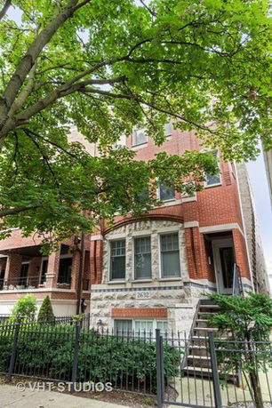 Front view of a multi-story brick house with steps leading to the entrance.