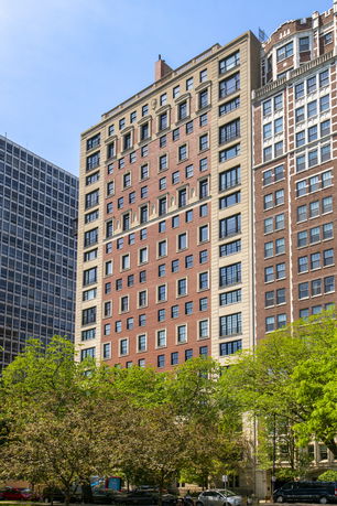 Front view of a tall brick building with multiple windows and decorative elements.