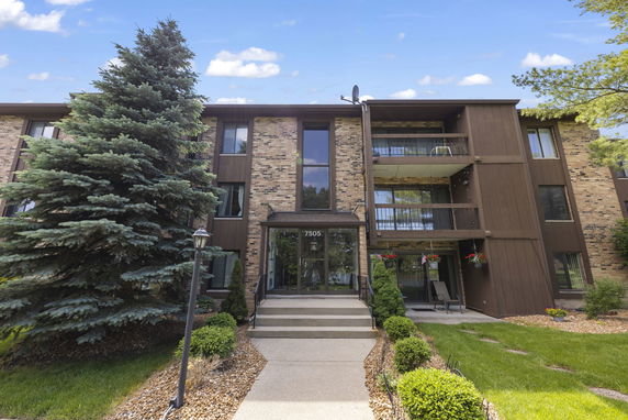 Front view of a multi-story residential building with a brick facade and balconies.