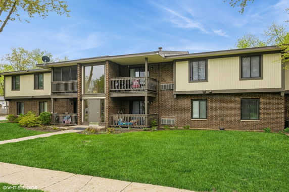 Front view of a two-story residential building with balconies and a brick exterior.