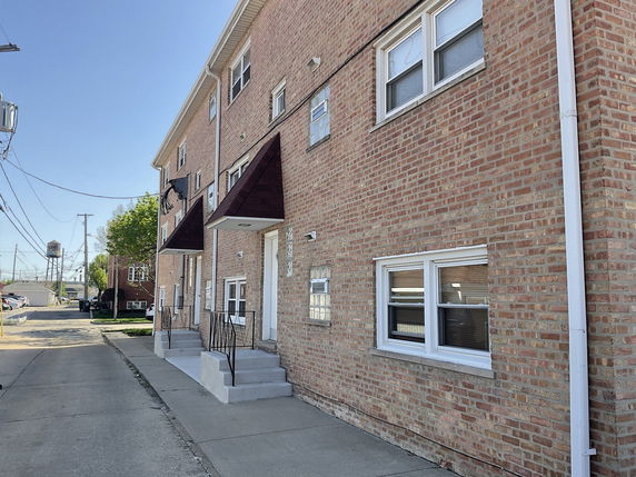 Front view of a multi-story brick building with two entrances and small awnings.