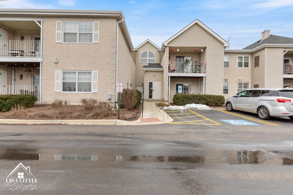 Front view of a multi-story residential building with balconies and a parking area.