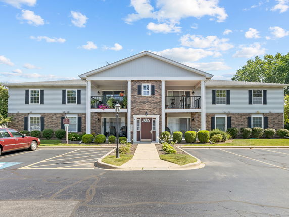 Front view of a two-story residential building with a parking area in front.