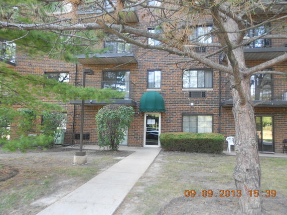 Front view of a multi-story brick apartment building with a green awning over the entrance.