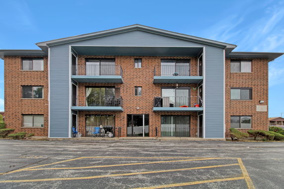Front view of a three-story brick building with balconies.