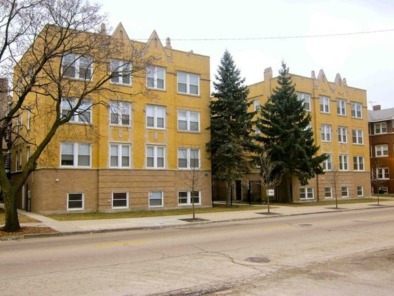 Front view of a multi-story apartment building with a yellow and brown facade.
