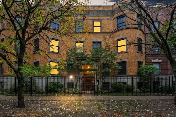 Front view of a multi-story brick building with a gated entrance.