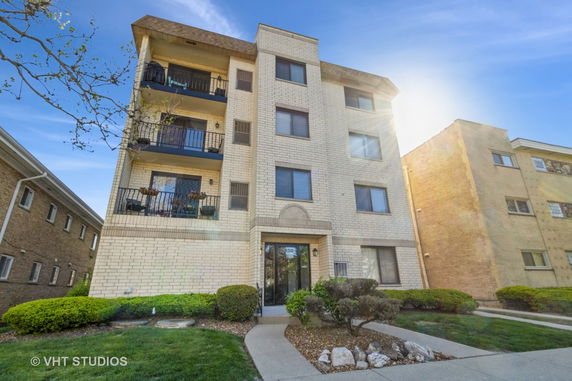 Front view of a four-story brick apartment building with balconies.