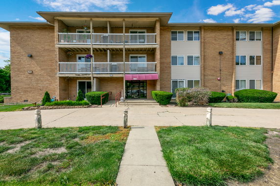Front view of a three-story apartment building with a central entrance and multiple balconies.