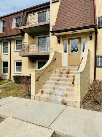 Front view of a multi-story building with a staircase leading to the entrance.