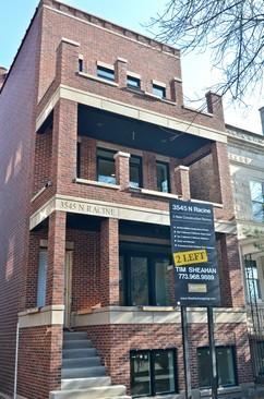 Front view of a multi-story brick building with a staircase leading to the entrance.