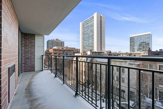 Panoramic view from a building balcony overlooking surrounding cityscape with high-rise buildings.
