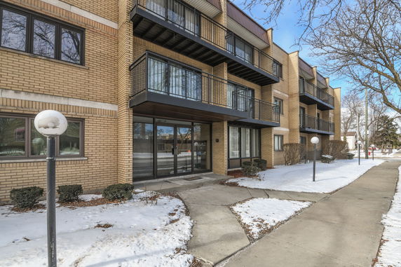 Front view of a multi-story brick apartment building with balconies.