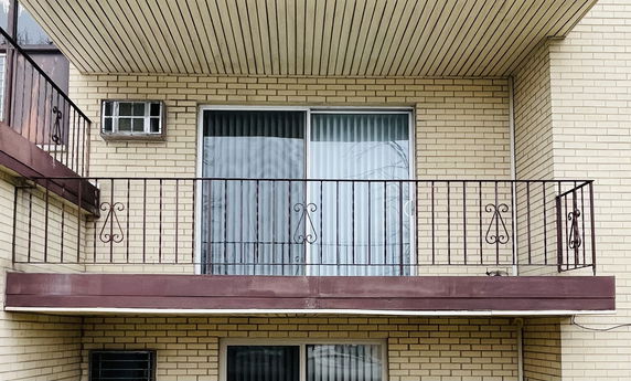 Balcony view of an apartment with sliding glass doors and an air conditioning unit.