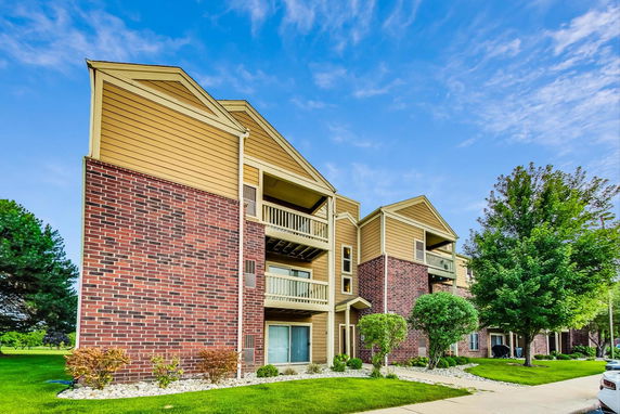 Front view of a multi-story apartment building with balconies and brick facade.