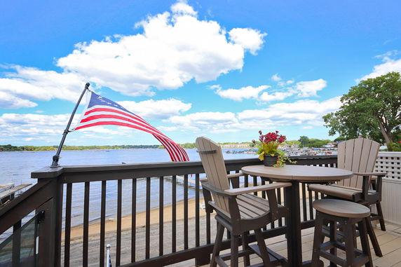 Panoramic view of a lake seen from a deck with chairs and a table.