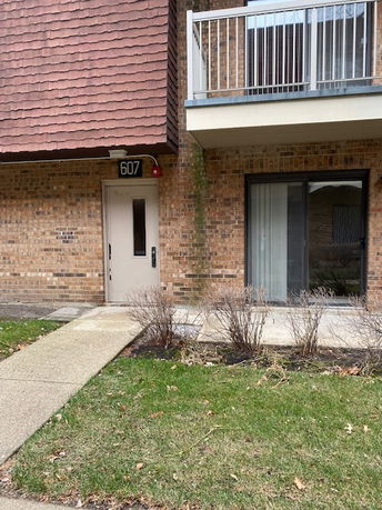 Front view of a brick apartment building with a balcony and entrance door.