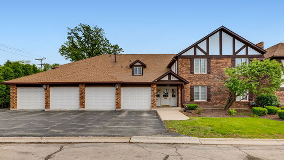 Front view of a two-story house with multiple garages and a brick facade.