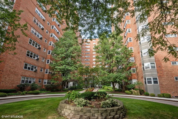 Front view of a multi-story red brick apartment building with numerous windows.