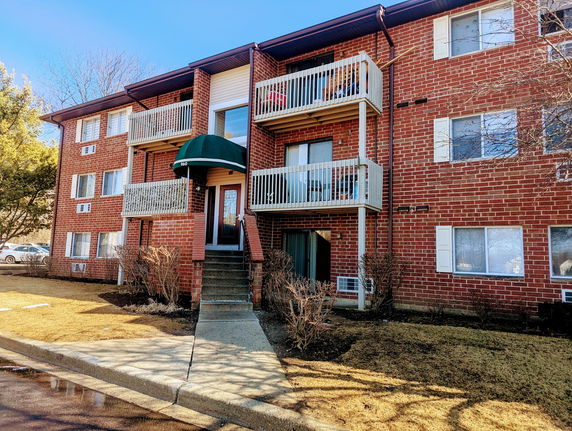 Front view of a multi-story brick apartment building with balconies.