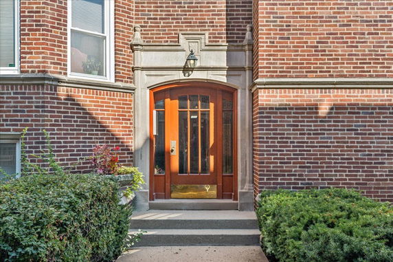 Front entrance of a brick building with an arched wooden door.