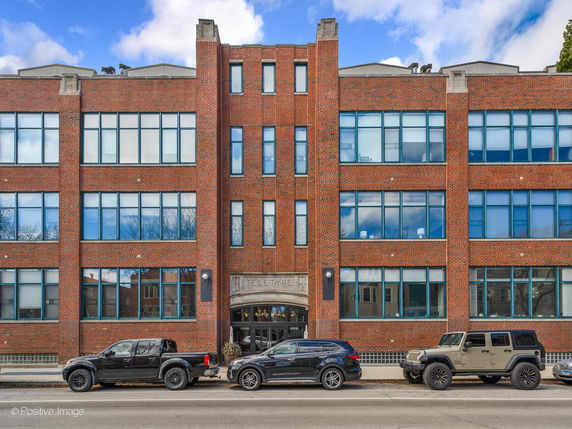 Front view of a multi-story brick building with large windows.