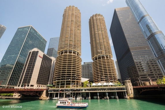 Front view of twin cylindrical high-rise buildings with a waterfront in the foreground.